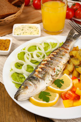 Delicious grilled fish on plate on table close-up