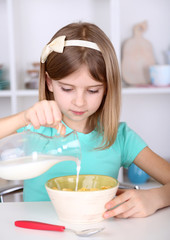 Beautiful little girl eating breakfast in kitchen at home