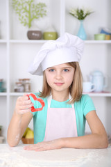 Little girl preparing cookies in kitchen at home