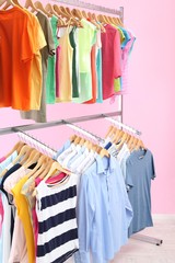Obraz premium Different clothes on hangers, on pink background