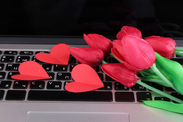 Red hearts and flowers on computer keyboard close up