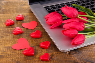 Computer with red hearts and flowers on table close up