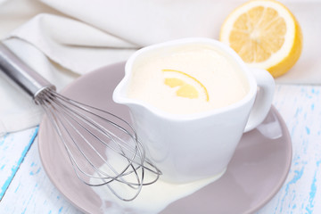 Delicate sauce in pitcher on wooden table close-up