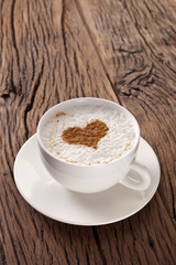 Cup of cappuccino with ground cinnamon in the form of heart.