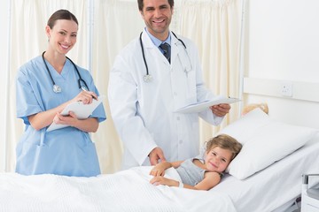 Obraz na płótnie Canvas Doctors with sick girl in hospital ward