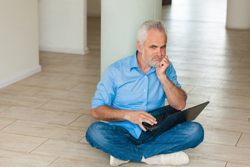 old man with notebook sitting on the floor