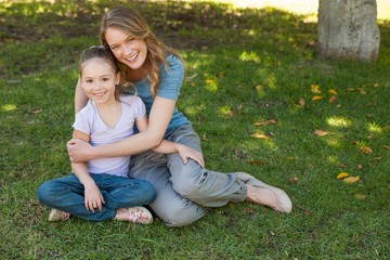 Fototapeta premium Smiling mother embracing her daughter at park