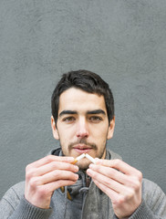 Portrait of man breaking a cigarette.