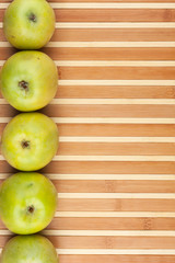 Green apples lie on  bamboo mat