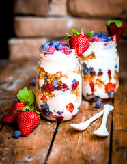 Granola Parfait with yogurt and berries on rustic background