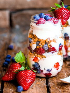 Granola Parfait with yogurt and berries on rustic background