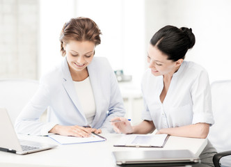 two smiling businesswomen working in office
