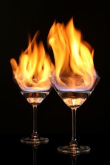 Glasses with burning alcohol on black background