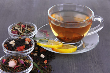 Cup of tea with aromatic dry tea in bowls on wooden background