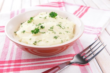 Delicious mashed potatoes with greens in bowl on table close-up