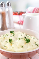 Delicious mashed potatoes with greens in bowl on table close-up