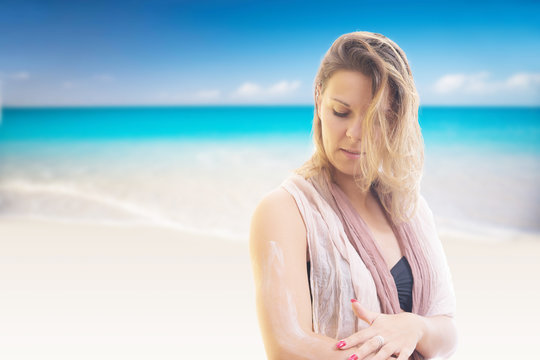 woman applying sunscreen at the beach