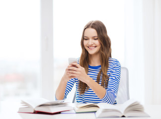 smiling student girl with smartphone and books