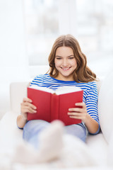 smiling teenage girl reading book on couch