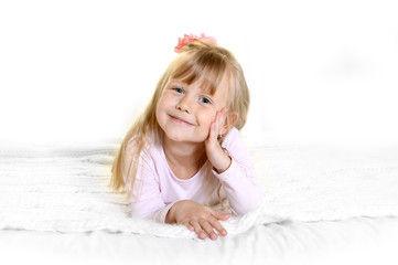 sweet  little blonde girl lying happy on bed