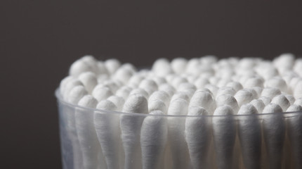 Bunch and separate cotton buds with plastic packing on a dark ba