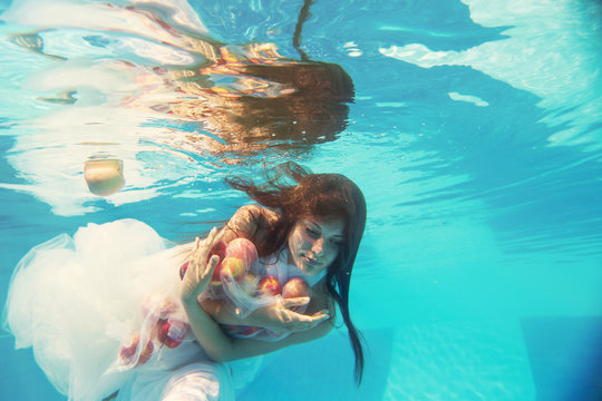 Beautiful woman under water with red apples