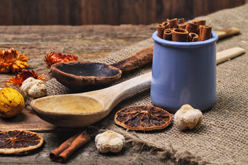 A jar of cinnamon sticks, wooden spoons and dried citrus