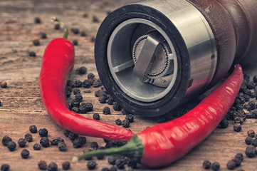A grinder with two chili peppers and allspice