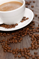 A cup of coffee and beans in a shape of a heart