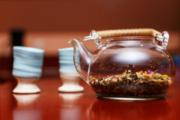 A glass teapot with tea and two clay glasses