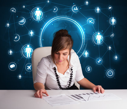 Businesswoman sitting at desk with social network icons