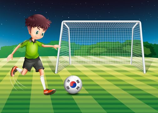 A boy kicking the ball with the South Korean flag