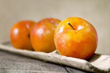 three yellow plums on wood