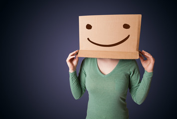 Young lady gesturing with a cardboard box on her head with smile