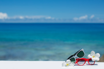 Two pairs of sunglasses on the background of blue ocean