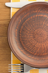 plate, knife and fork at napkin on wood