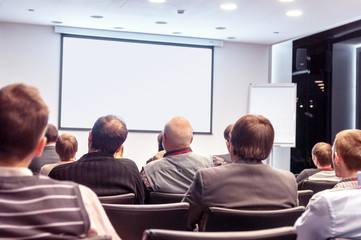 people sitting rear at the conference and looking at the screen