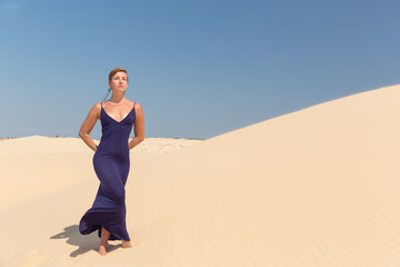 Beautiful woman in blue dress in sand dune