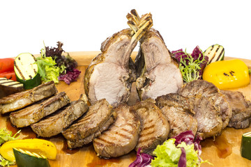 loin and steak cooked on a grill with vegetables