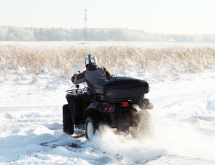 man driving a quad bike in the winter field