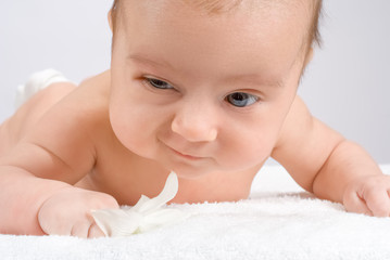 A cute little baby with flower on white blanket