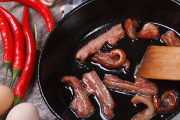 fried bacon in a pan and chili, horizontal. macro