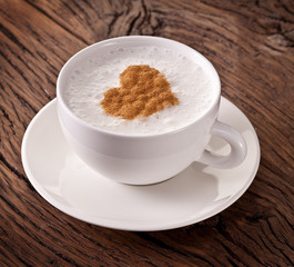 Cup of cappuccino with ground cinnamon in the form of heart.