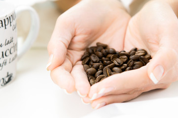 Womans Hands full of roasted coffe beans shaped as heart