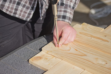 Man is bolting  screwed into a wooden board.