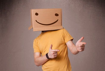 Young man gesturing with a cardboard box on his head with smiley