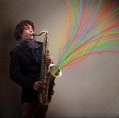 Obraz na płótnie Canvas Attractive musician playing on saxophone while colorful abstract