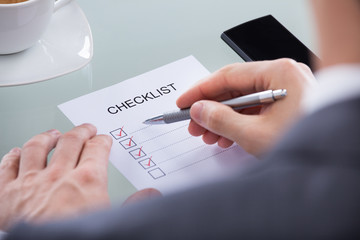 Businessperson With Pen Over Checklist