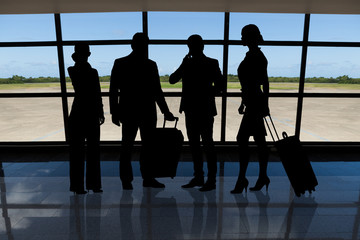 Businesspeople with luggage standing against airport window