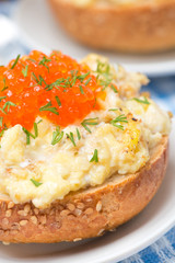 scramble eggs with red caviar on a wheat bun, close-up
